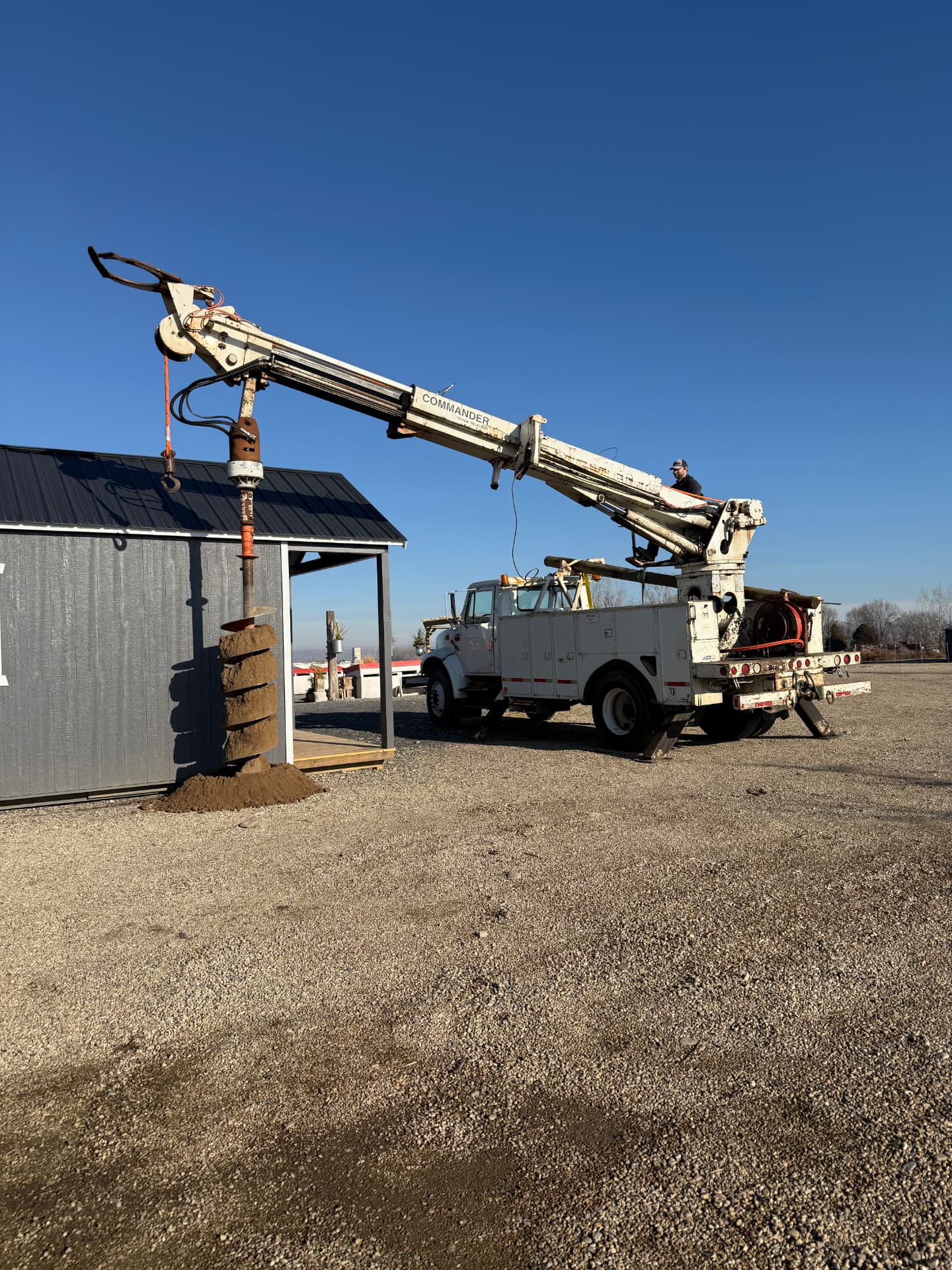 Auger truck drilling a post hole on a gravel lot